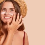 Donna che spalma la crema solare sul viso