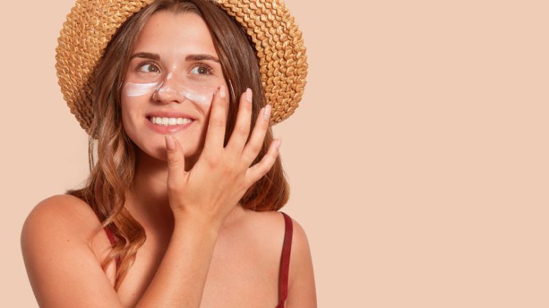 Donna che spalma la crema solare sul viso